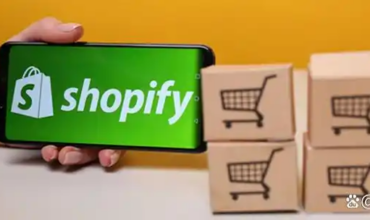 Hand holding a mobile phone with Shopify logo next to cross-border shipping boxes